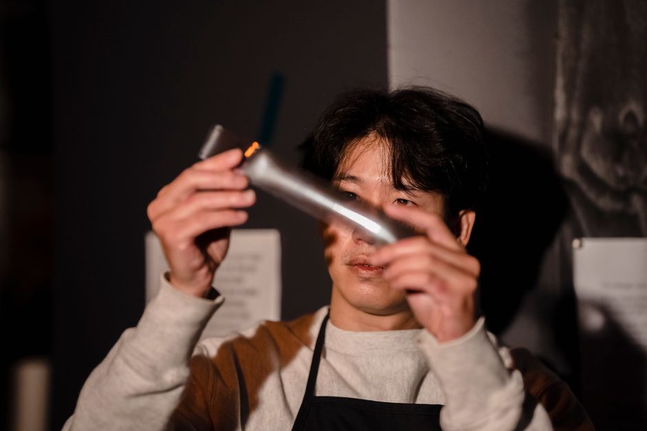 한 사람이 주방에서 현대적인 정수기의 물 추출구 노즐을 조심스럽게 청소하고 있습니다.